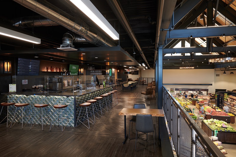Clean and organized public eating area with stools, tables, chairs and brushed metal accents