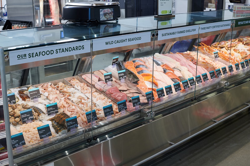 Brightly lit case filled with different kinds of fresh seafood and meat